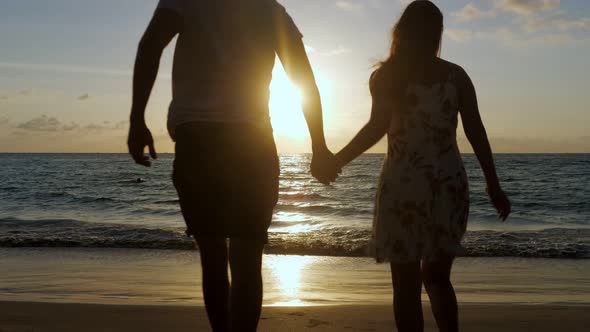 Silhouette of Young Family Running Along Beach To Ocean