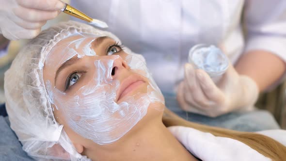 Beautiful Woman with Facial Mask at Beauty Salon