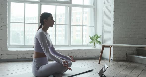 Young Woman Meditating Using Tablet Mobile App for Breathing and Meditation