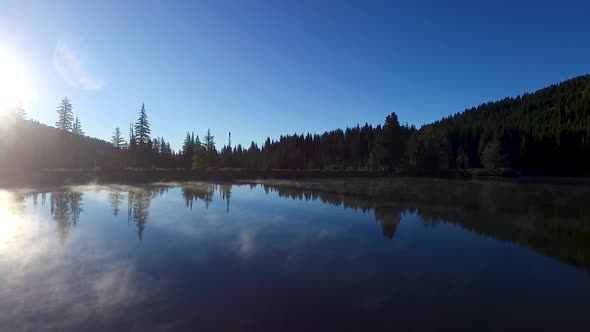 Steam slowly raises off a high mountain lake in the morning sun