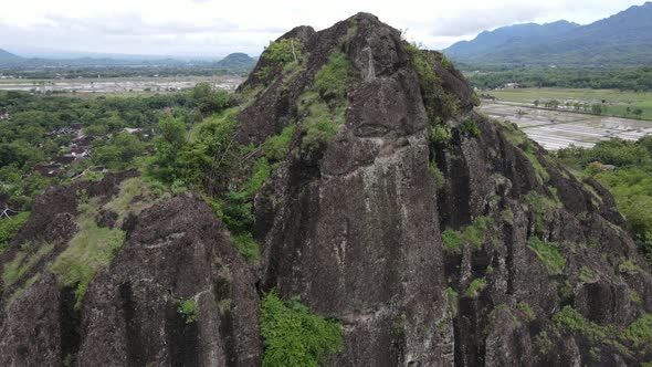 Aerial drone view of rock mountain cliff in the middle of the rice field.