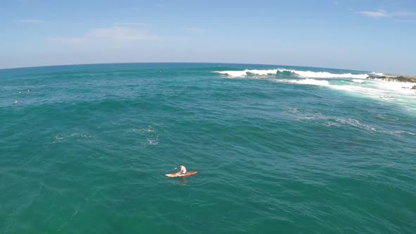 Aerial view of a man sup stand-up paddleboard surfing in Hawaii