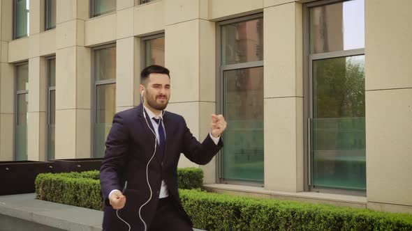 Young Businessman with Sunglasses Listening To the Music on His Smartphone Outdoors and Dancing. He