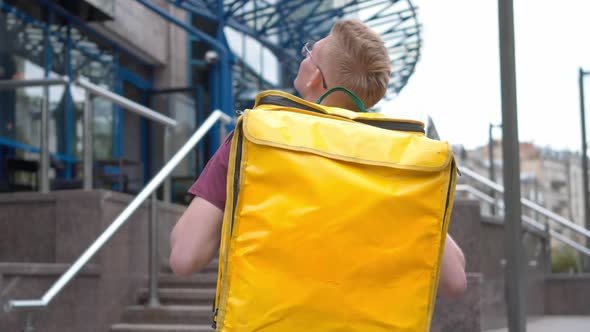 Yellow Thermal Backpack on Male Courier Standing in Front of Business Center Waiting