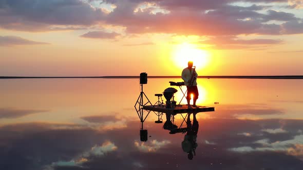 Saxophonist Is Playing on a Small Raft in the Sea During Sunset, Gorgeous View