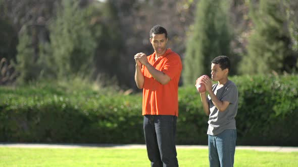 A father teaching his sons how to play American football.