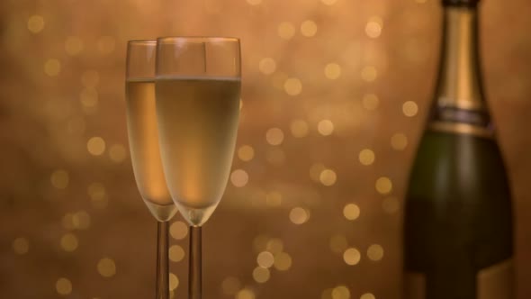 Champagne glasses over holiday bokeh blinking background, rotating on turntable