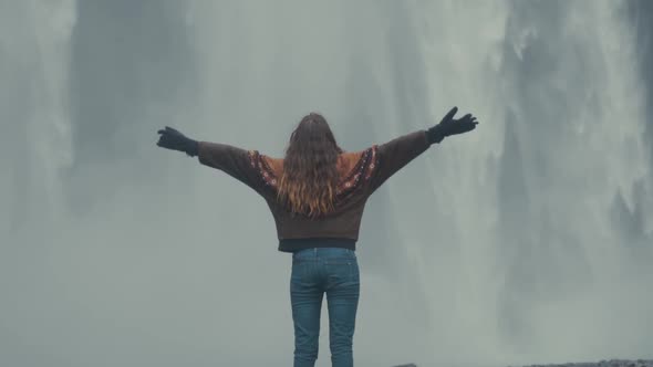 Woman standing on rock against amazing waterfall