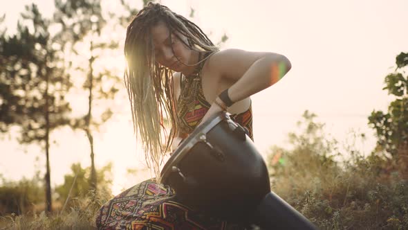 Beautiful Young Hippie Woman with Dreadlocks Playing on Djembe
