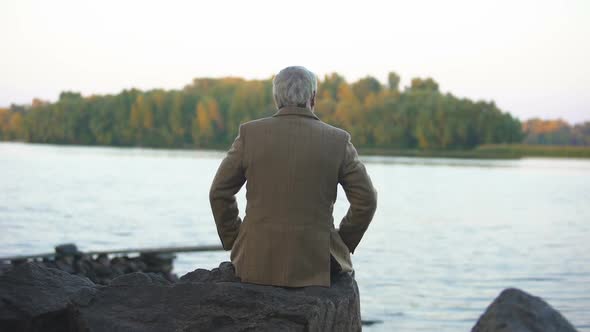 Aged Male Sitting on Stone River Bank, Thinking of Life, Enjoying Nature View