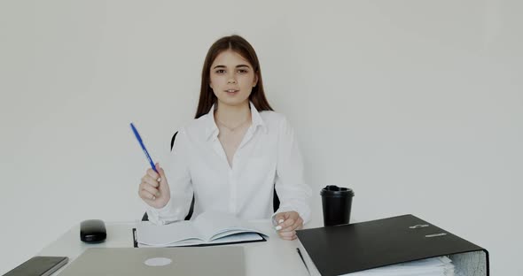 Happy Office Girl Talking with Smile and Pen in Hand for Camera at Workplace