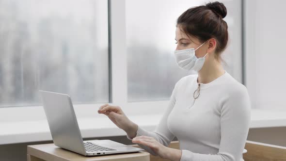 Young Business Woman in Face Mask Communicating By Video Call on Laptop Computer. Online Conference