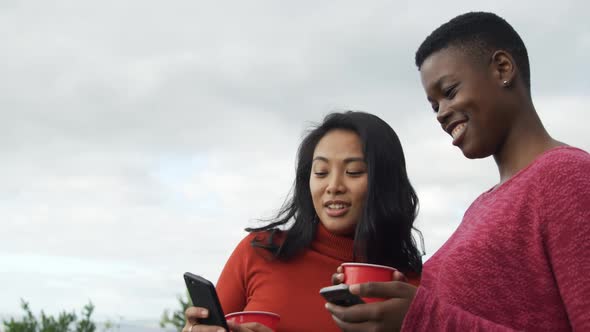 Young women using smartphones on a rooftop