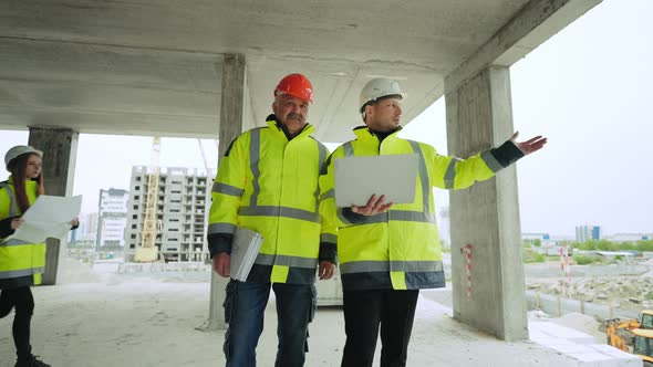 Two Male Civil Engineers are Viewing Underconstruction Building Professional Builders are