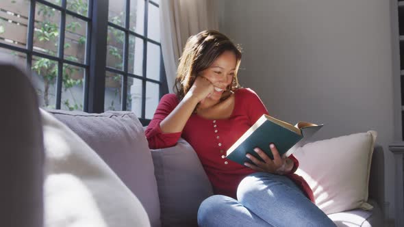 Mixed race woman reading a book. Social distancing and self isolation in quarantine