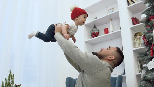 Oving Father Holding His Cute Infant Up in the Air in the Room