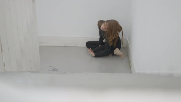 Young Woman Sits in Corner of Stairwell and Moves with Hair in Face