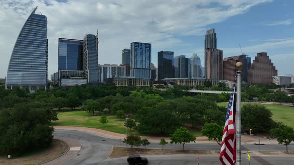 Aerial truck shot of United States flag in front of American city Austin, Texas. City skyline and gr