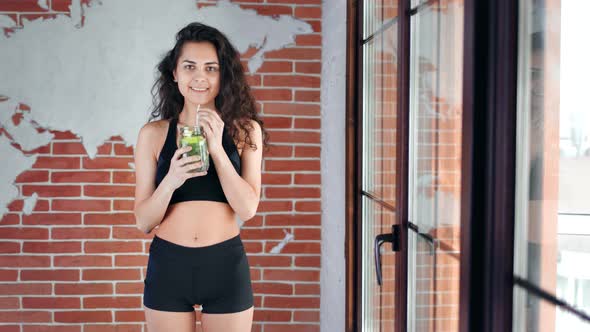 Smiling Beautiful Hispanic Fitness Girl Drinking Fresh Cocktail Looking at Camera