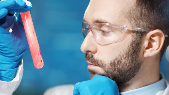 Closeup Face of Confident Male Chemic Doctor Looking on Spreading Red Blood in Beaker