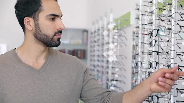 Glasses Shop. Man Trying On Eyeglasses In Optics Store