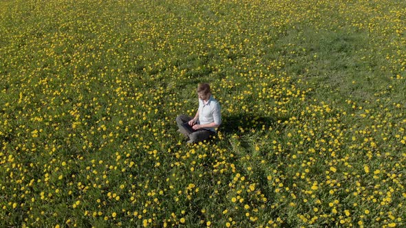 a Man with a Laptop Works in the Middle of the Field