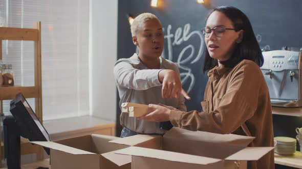 Saleswomen Unpacking Boxes With Inventory For Coffeeshop