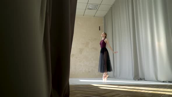 Young Ballerina in Burgundy Swimsuits and Long Black Skirt Rehearsing in a Ballet Studio. Flexible