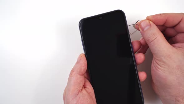 Men's Hands Insert a SIM Card Into a Smartphone