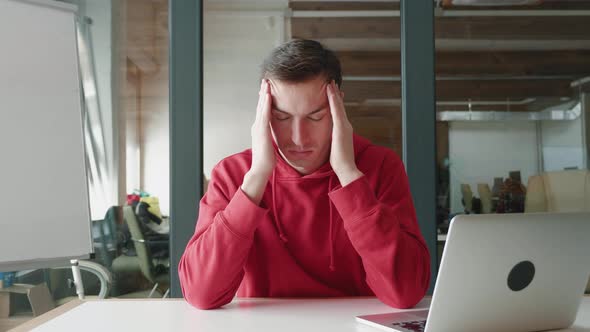 Stressed Young Man Suffering From Headache Feelings Due To Overwork Worried About Problems at Work