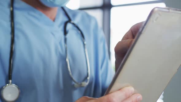 Caucasian male doctor wearing face mask using digital tablet