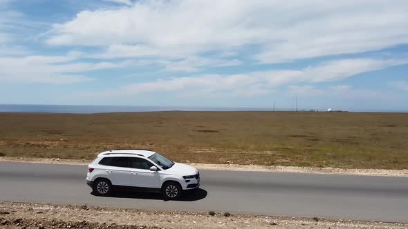 Travel on a Long Straight Road Through the Steppe. The Car Goes on a Sunny Summer Day.