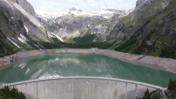 Flight from the huge dam to the emerald green mountain lake lac de tseuzier in the swiss mountains