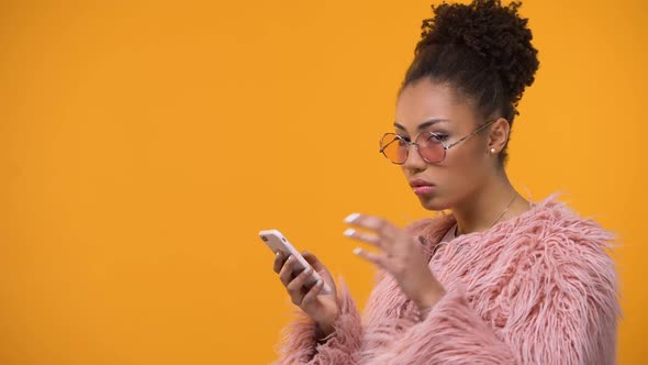 Glamorous Girl Scrolling Web-Pages on Smartphone, Isolated Yellow Background