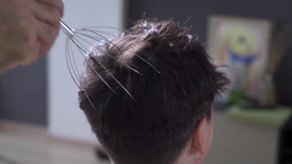 A Man Massages His Own Scalp with a Scalp Massager