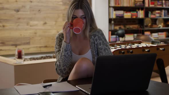 Caucasian woman drinking coffee while working