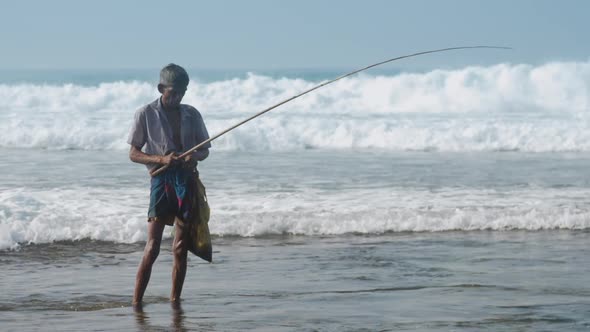 Local Man Holds Fishing Rod in Hand Against Waving Ocean