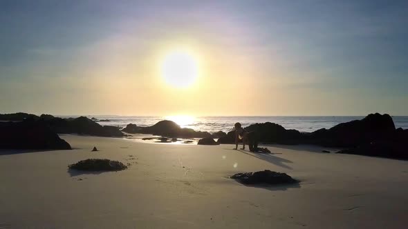 Girl Silhouette Does Yoga on Beach Against Sunrise