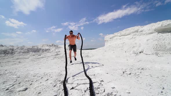 Athlete doing cross fitness workout outdoor. Battle rope training as functional fitness on nature