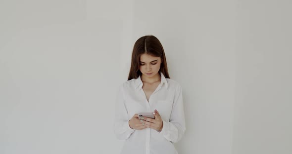 Portrait of Young Girl Typing on the Smartphone on White Background