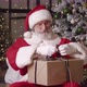 Handsome Elderly Santa Claus Concentrating on Packing a Gift Box Trying to Tie a Bow with a Satin - VideoHive Item for Sale