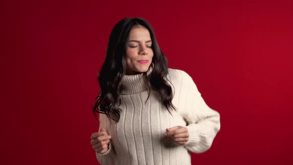 Pretty Girl in Sweater Smiling and Dancing in Excellent Mood on Red Background