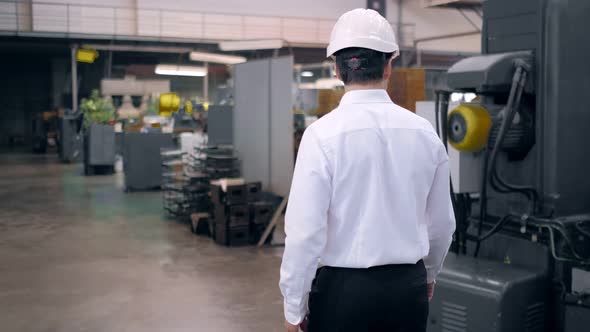 Shot of Professional Factory Worker Wearing Hard Hat Holds Tablet Computer Walking Thorugh Modern