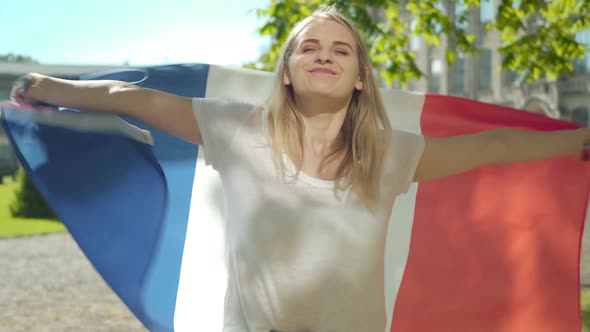 Blond Positive Caucasian Woman Spinning with French Flag on University Yard. Portrait of Charming