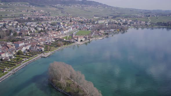 Aerial shot over the lake in front of Rolle Castle, Switzerlandîle de La Harpe in the foreground, S