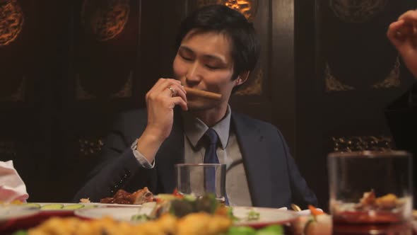 Businessmen toasting glasses and smoking sigars in Chinese restaurant