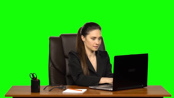 Woman Enthusiastically Works Behind a Laptop, Smiles and Enjoys the Result. Green Screen