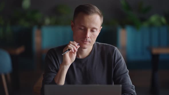 Thoughtful Serious Young Man Student Writer Sit at Home Office Desk with Laptop Thinking of