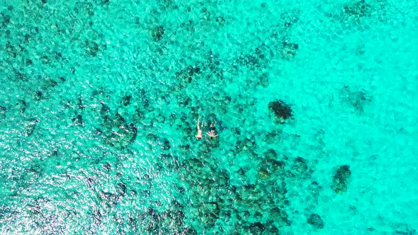 Wide angle fly over island view of a white sandy paradise beach and aqua blue ocean background in hi