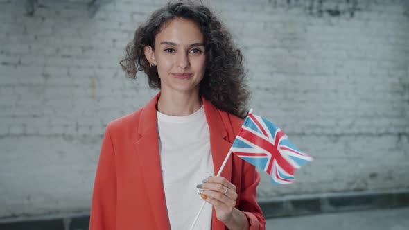 Slow Motion of Attractive Girl Holding British Flag Outdoors Smiling Looking at Camera on Windy